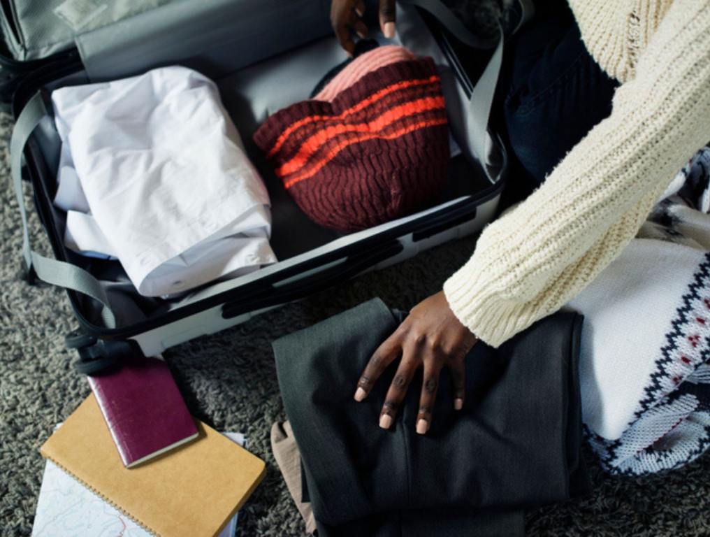 person folding clothes and packing suitcase for vacation and travel