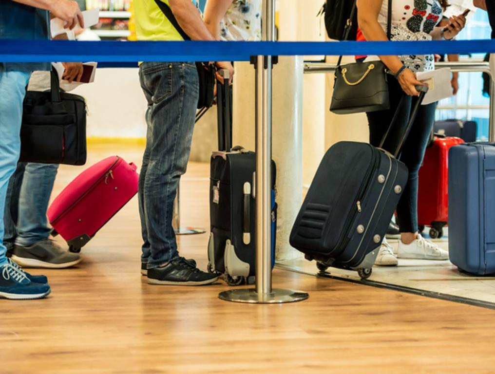 4 tips to help with CLT Airport Spring Break Crowds. Pictured travelers in long line with luggage