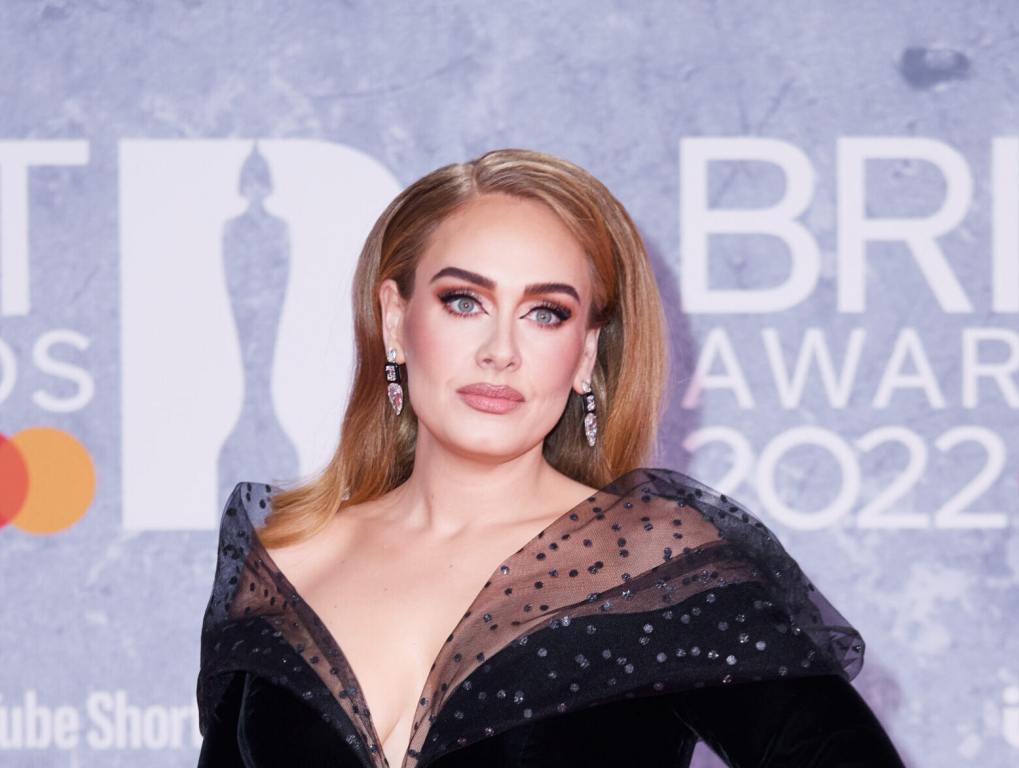 Adele attends The BRIT Awards 2022 wearing a black gown looking right.