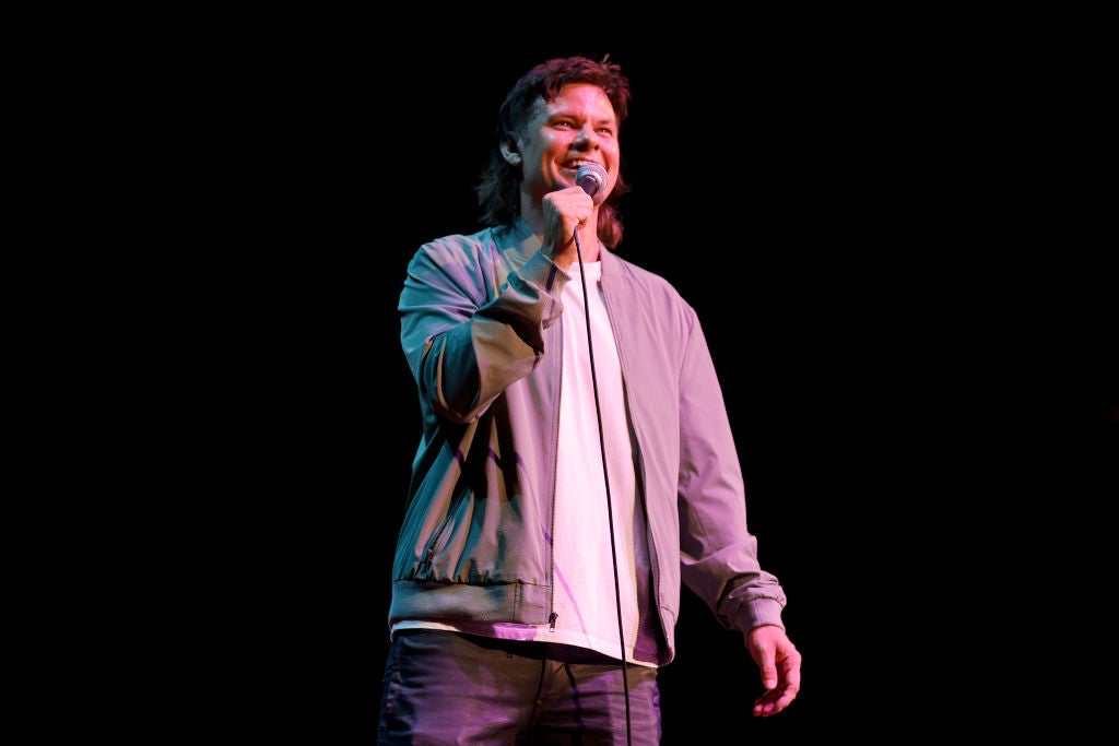 Comedian Theo Von on stage doing stand-up comedy.