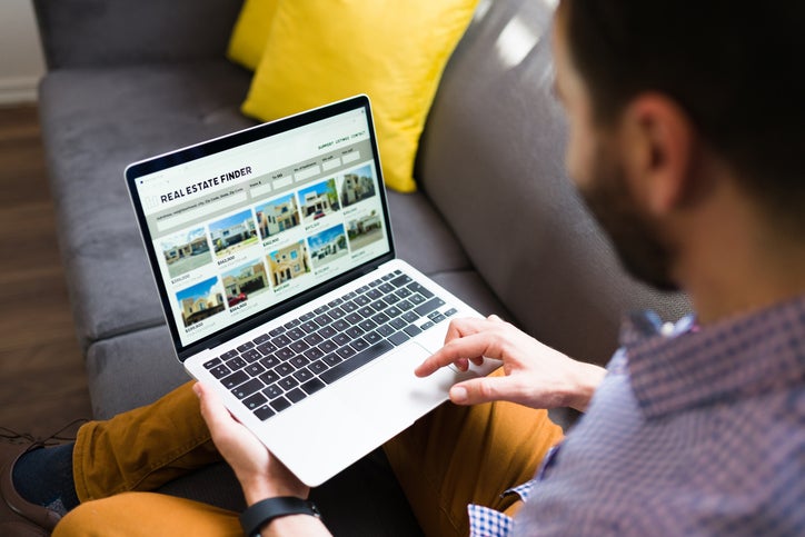 ear view of a man looking for new houses on sale online. Young man using a real estate website on the laptop online home searchers