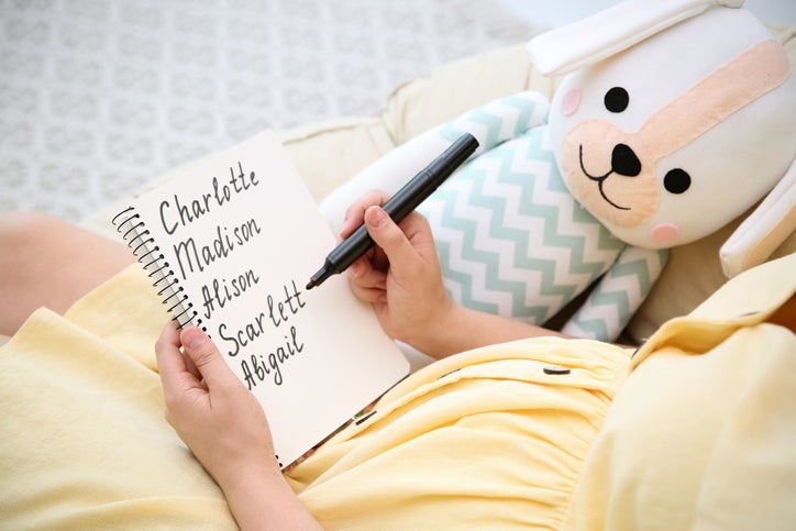 Pregnant woman with baby names list sitting in armchair, closeup. Popular city names for children