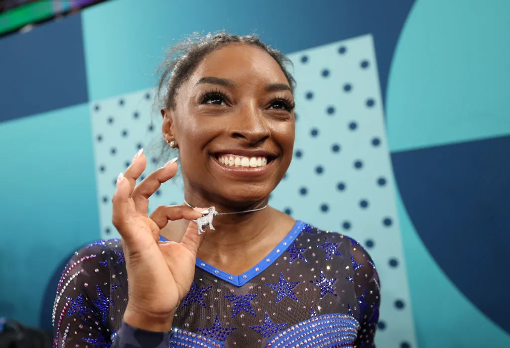 Gold medalist Simone Biles of Team United States poses with a necklace in the likeness of a goat after competing in the Artistic Gymnastics Women's All-Around Final on day six of the Olympic Games Paris 2024 at Bercy Arena. So, what's the story behind Simone Biles' goat necklace?