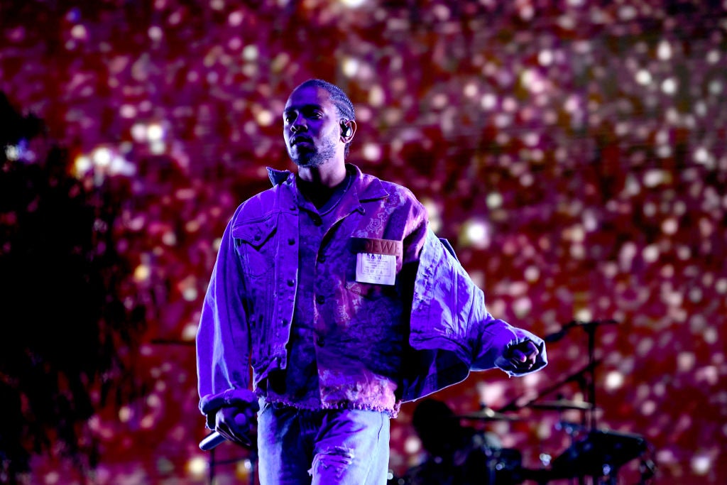 Kendrick Lamar performing on stage wearing a denim jacket