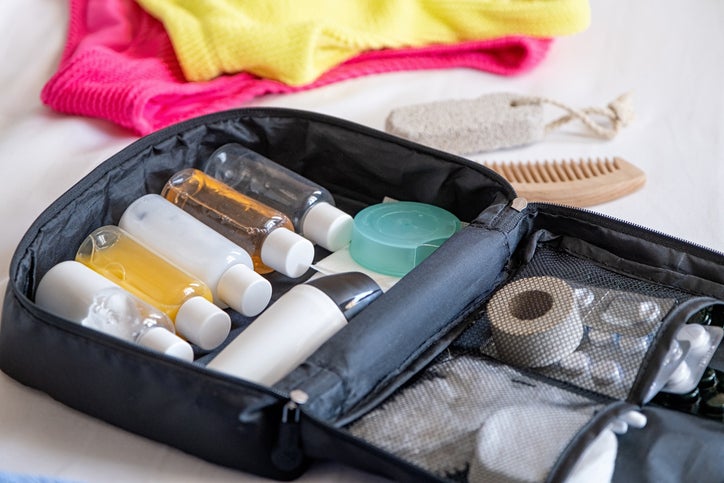 Travel cosmetics kit with bottles, pills and cosmetics on bed