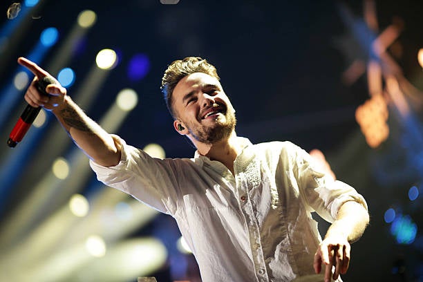 Liam Payne of One Direction on stage holding one arm in the air with lights in the background. Liam Payne's Final Days