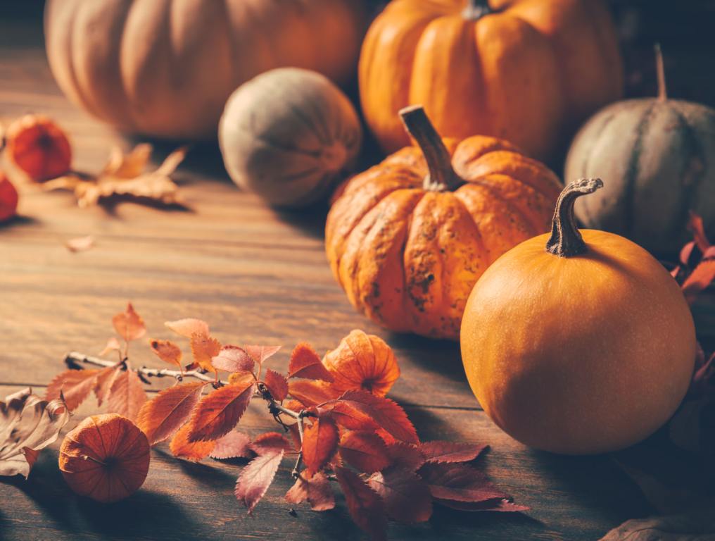 Pumpkins and fall leaves on a table top.