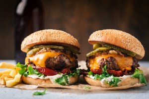 Two juicy craft cheeseburgers with roasted bell pepper and pickles